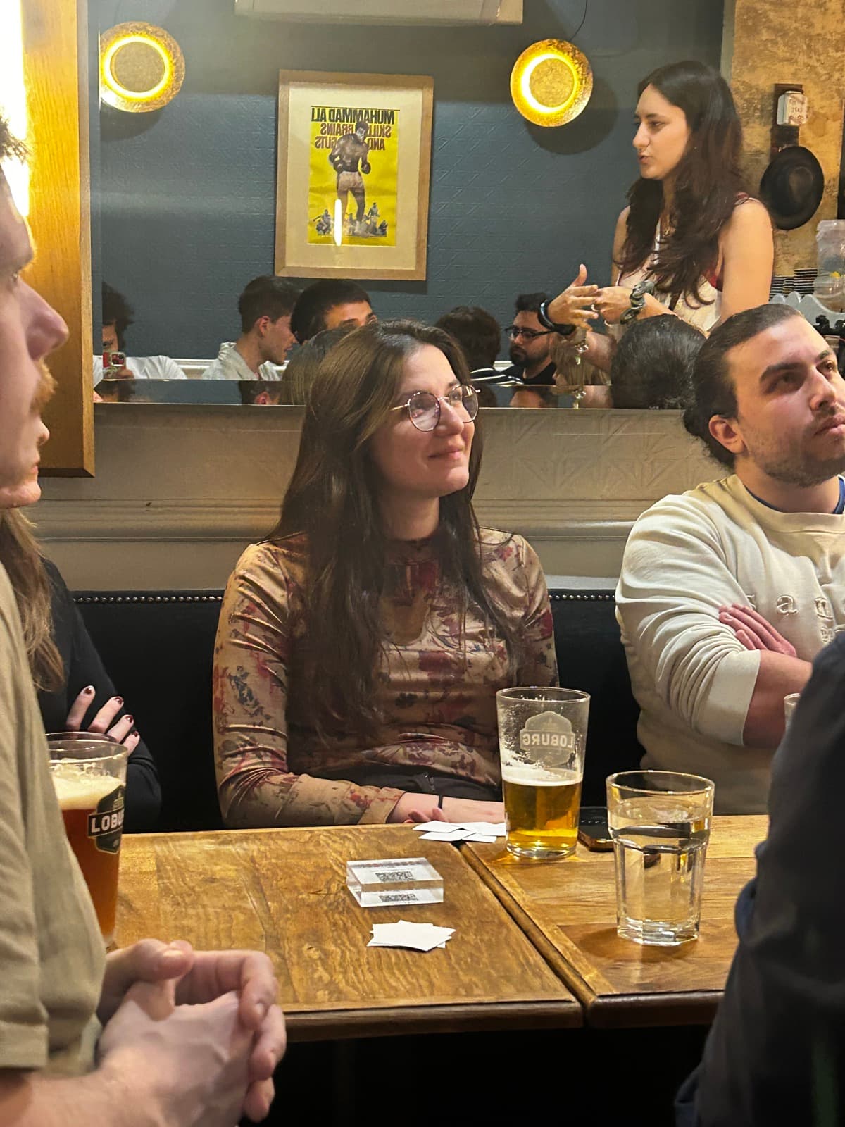 People around a wooden bar table at a Hold My Club quiz night
